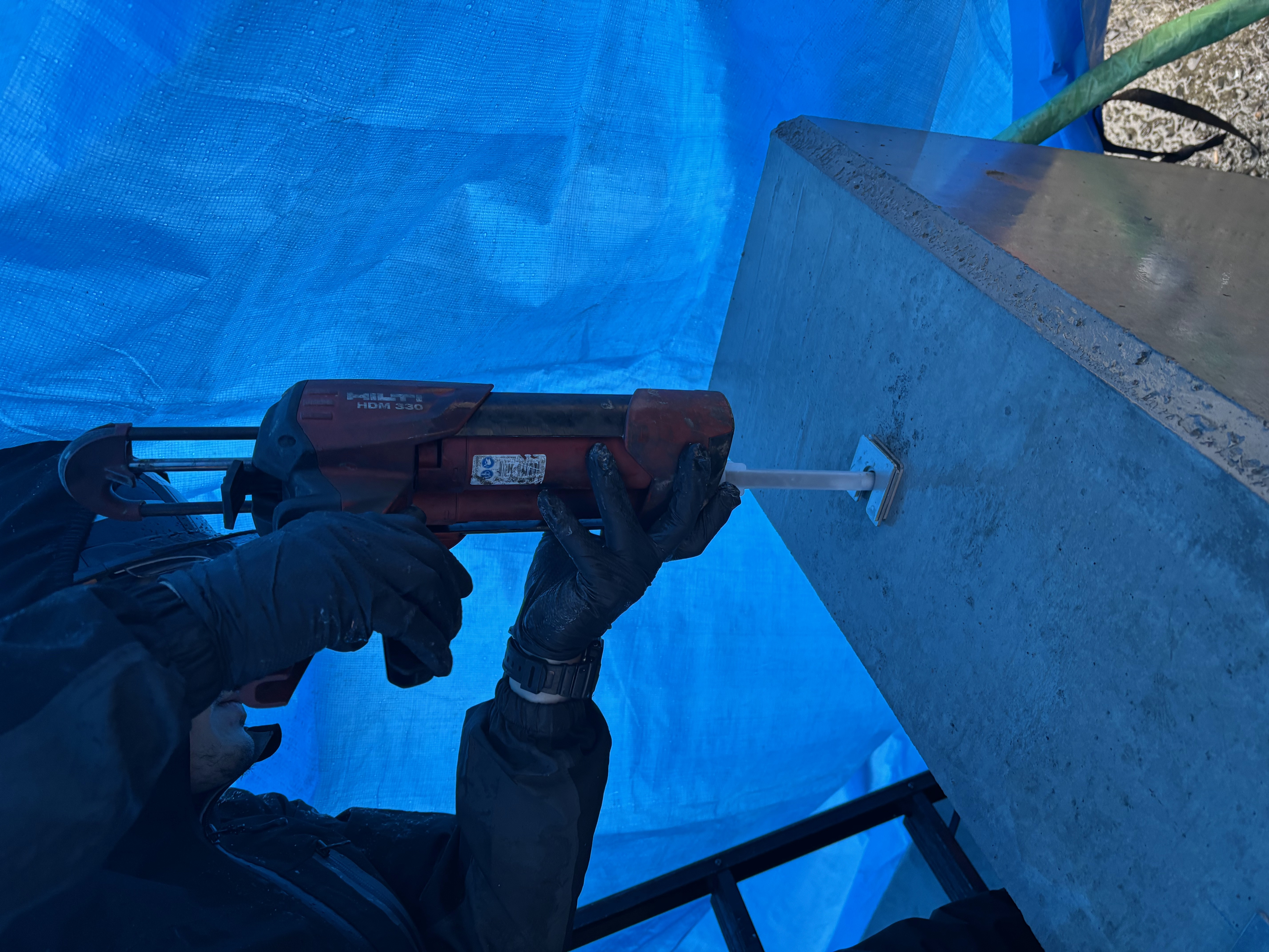Hilti HDM 330 でケミカル樹脂を注入。アンカー孔にディスペンサーのノズルを差し込んで注入している様子