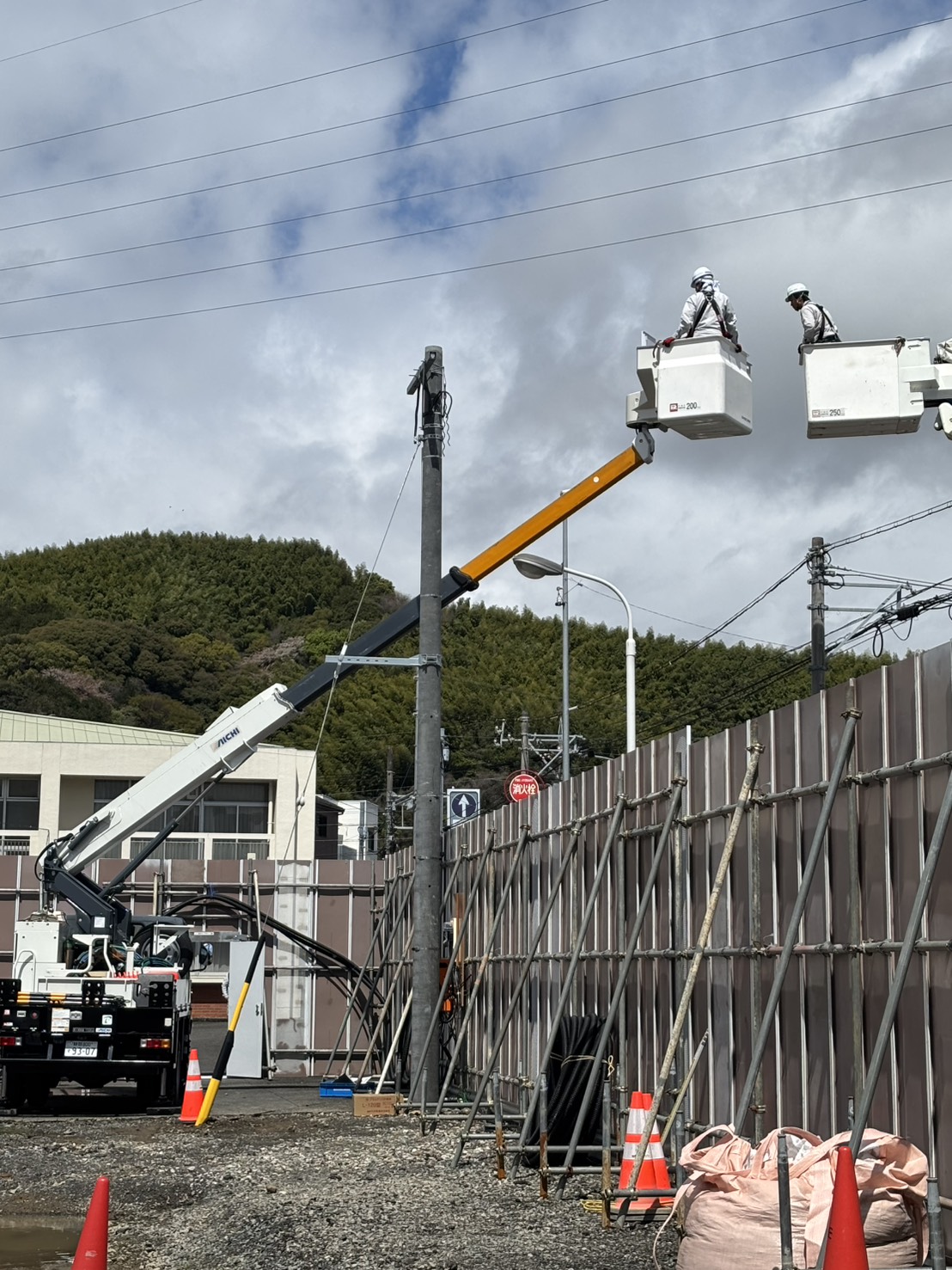 高所作業車2台で引込柱にDV線を接続している様子