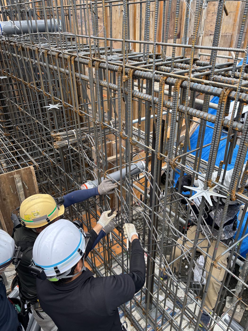 地中梁の配筋にあわせて電気配管用スリーブを取り付けている様子